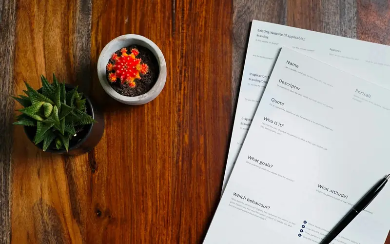 A wooden table topped with papers and a pen